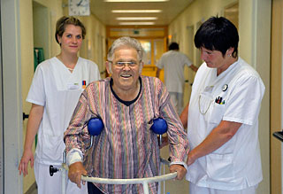 Patientin gestÃ¼tzt von zwei Schwestern beim gehen auf dem Krankenhausgang