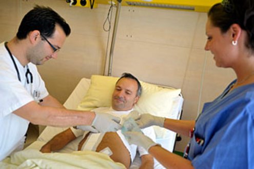 Arzt und Pflegerin legen einem Patienten den Verband an