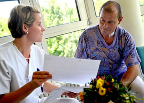 Pflegerin zeigt Patient etwas in einem Dokument