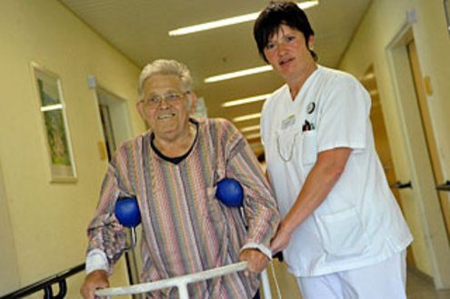 Pflegerin stÃ¼tzt Patienten beim Laufen